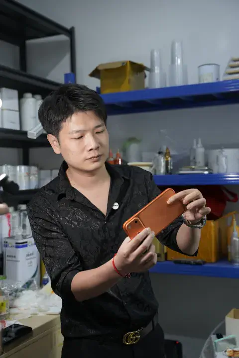 工作人员展示完成处理的橙色手机边框